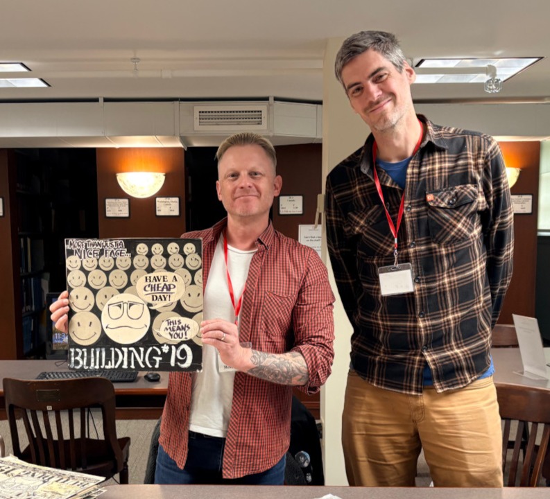 Image of Randy and Tripp holding a Building 19 advertisement mock-up.