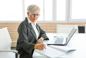 Woman Writing While on Laptop