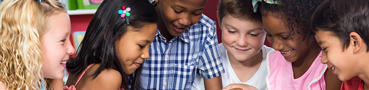 A group of children in a library gather around a tablet computer