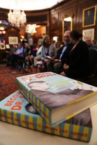 Stack of Becoming Dr. Seuss books with crowd in background