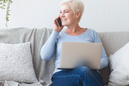 Researcher on couch with laptop takes a phone call