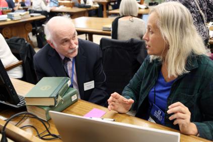 Two researchers in a library with a laptop and books