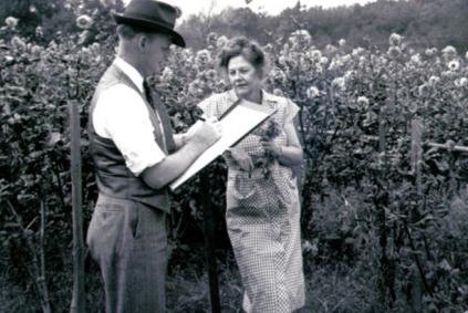 Man with a clipboard talking to a woman in a field