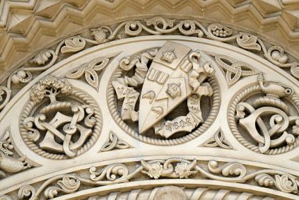 Stone carving on a 19th century building with coat of arms and educational heraldry and symbols